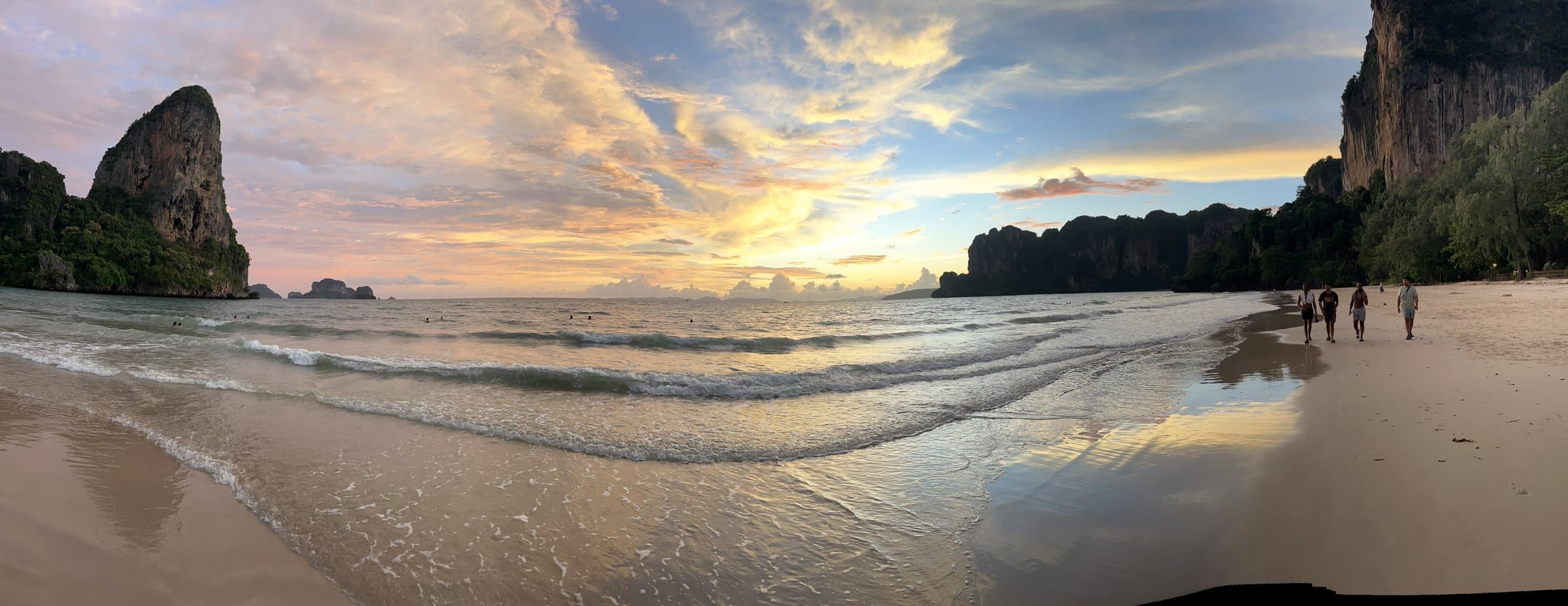 A wide view of the beach at sunset, wet sand reflecting the sky