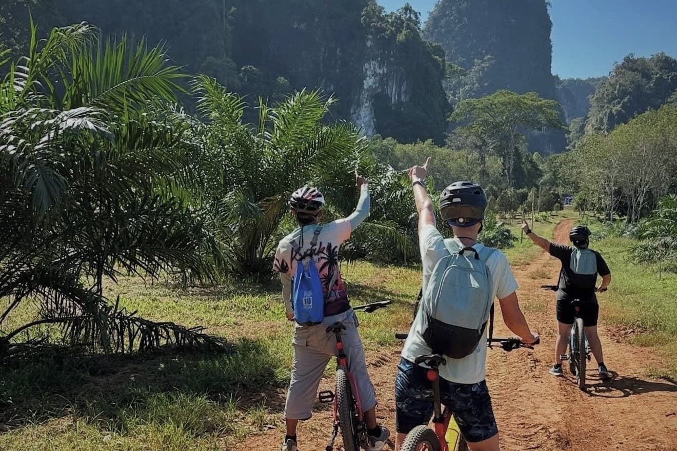 Riders on a red-earth track pointing at the limestone peaks