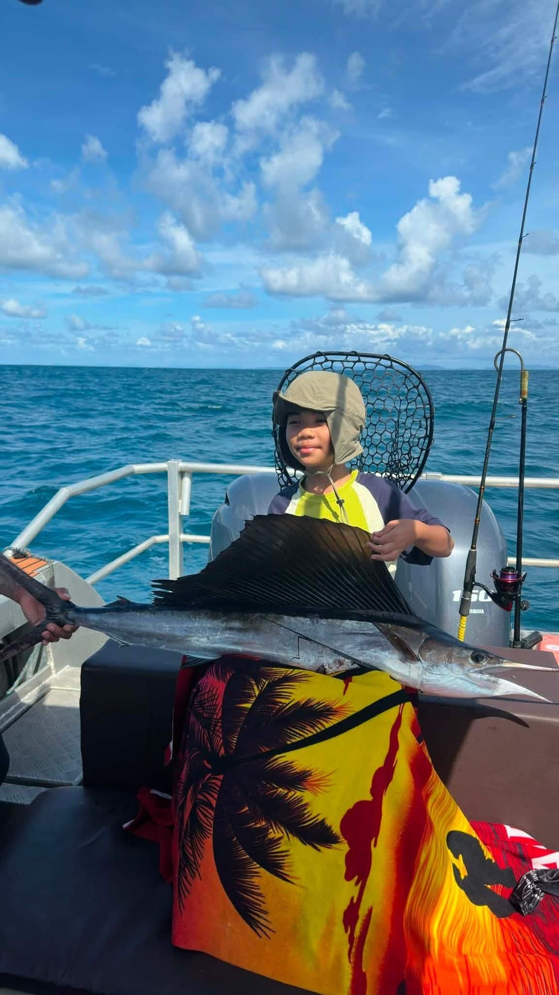 A young angler with a sailfish alongside the boat