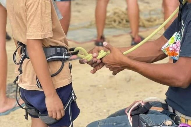 A guide ties a young climber into the rope