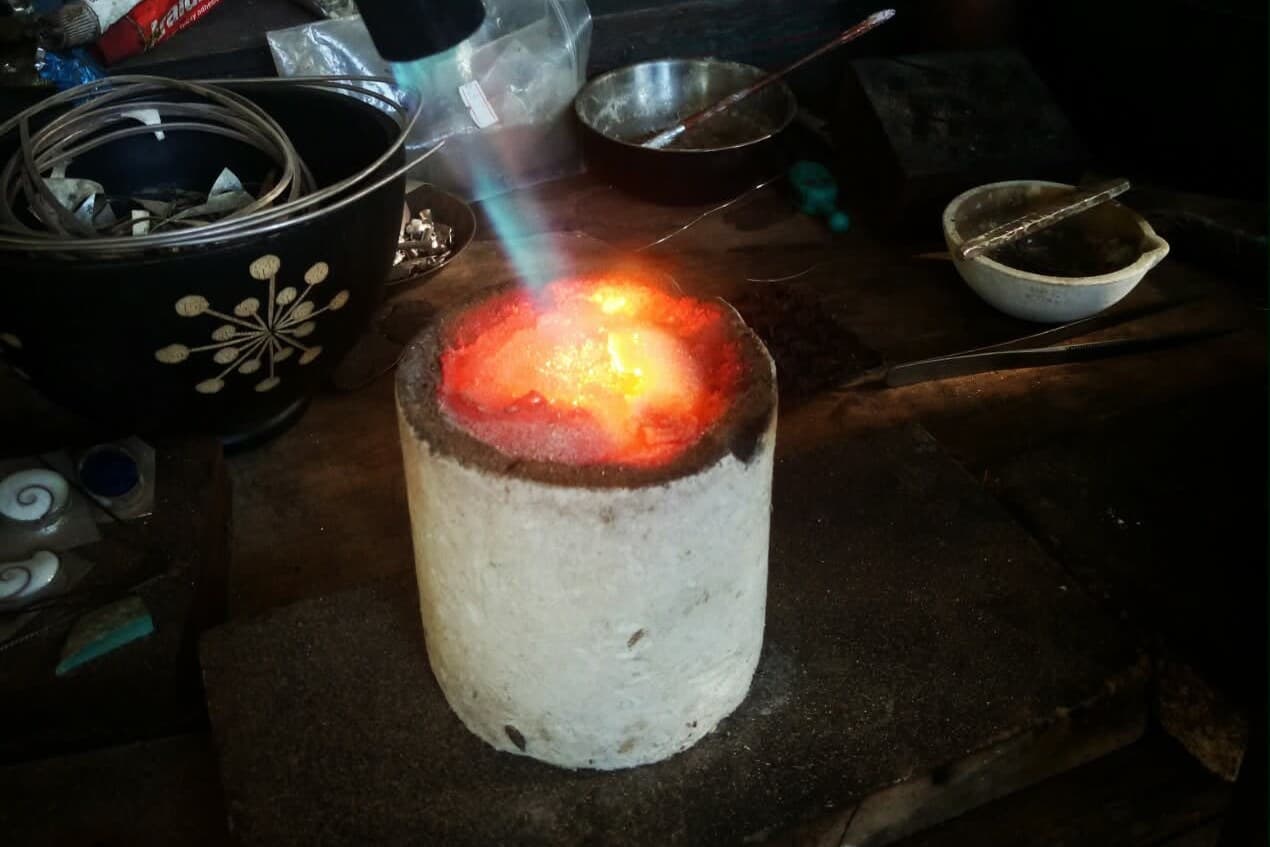 Melting silver in a crucible at the workshop bench