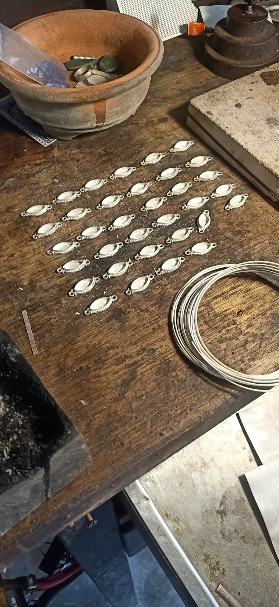 Handmade silver pendant settings laid out on the bench