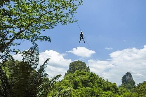 Flying the zip wire above the trees, limestone peaks behind